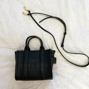 The tote bag Marc Jacobs  - Säljer min lilla söta tote micro väska i svart läder från Marc Jacobs. Den är äkta, köpt från Zalando i julas. Nypris var kring 4000kr. Knappt använd! Superbra skick. 