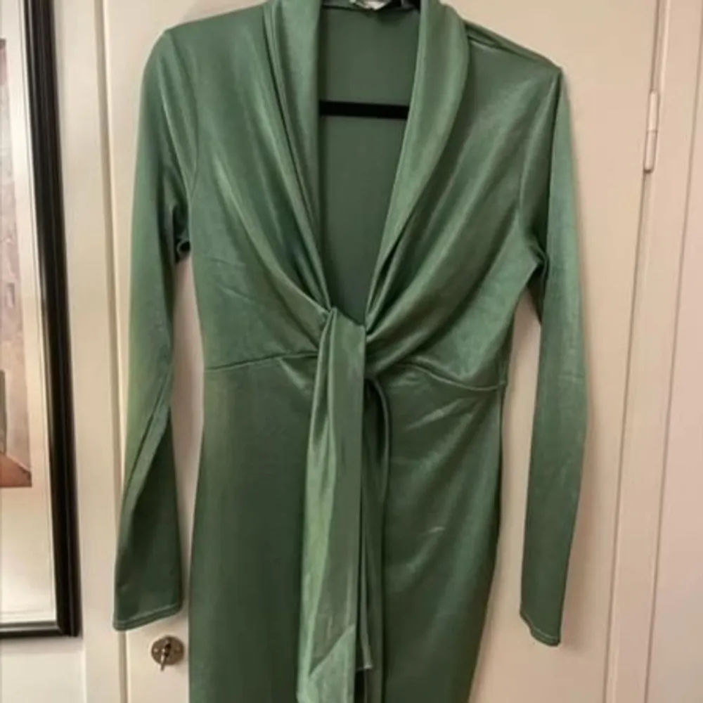 Säljer en underbar grön klänning från Asos, perfekt för alla tillfällen. Klänningen har en smickrande knytdesign och är i storlek 40.. Klänningar.