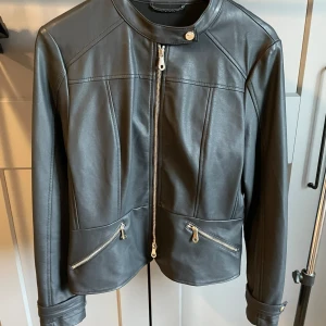 Skinnjacka i PU - Skinnjacka i imitation. Aldrig använd. Storlek 42, mindre i storlek likt en 40.