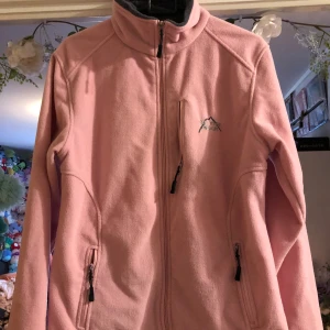 Rosa fleece tröja - Inga fel utom fickan på bröstet får jag ej att funka  Liten i storleken 