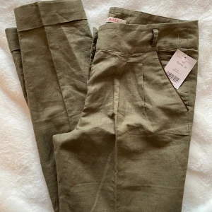 Nya kakifärgade halvlinne byxor i strl 36 från Camaieu - Nya kakifärgade halvlinne byxor i strl 36 från Camaieu.  Nya, med prislappen kvar   Mått Midjan: ca 37 cm Längd från grenen och ner: ca 66 cm  55% linne och 45% bomull 