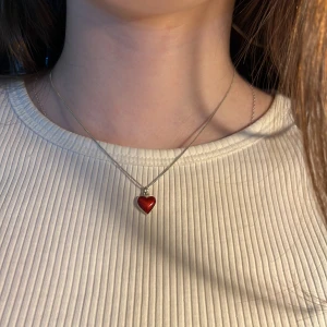 Silverhalsband  - Säljer ett äkta silverhalsband med ett rött hjärta på. Halsbandet har en 925 stämpel. Vid köp av andra smycken kan frakt kombineras. Skriv vid frågor.