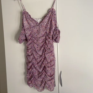 Söt sommarklänning  - Figursydd blommig kort klänning med ”puffiga” ärmar. Dragkedja i bak och axelbanden går att justera. Den är liten i storleken och passar därför någon med str.36/xs
