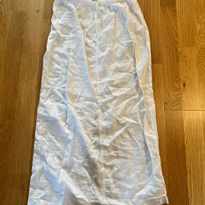 Vit Midi/Maxi Linnekjol  - Vit linnekjol från Pull&Bear. Kjolen går ner till smalbenen på mig som är  163 cm lång. Den har en slits baktill. Inköpt förra sommaren, bra skick. Kjolen har ett resårband med knyte i midjan. Storlek XS. Köparen står för frakten.