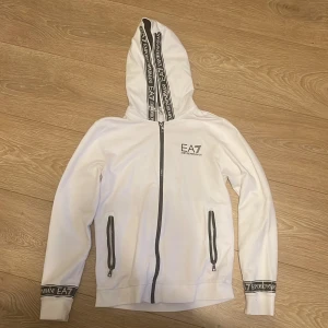EA7 zip up - Äkta Armani (EA7) vit zip up tröja med svarta glansiga detaljer. Storlek M. Perfekt kondition.