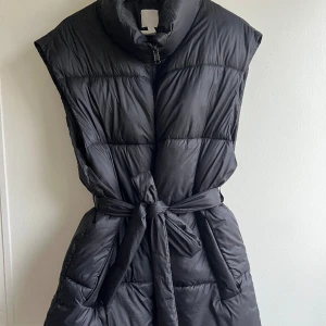 Dunväst från H&M med skärp - Superfin dunväst från H&M med skärp.  Storlek S, man kan använda den utan skärp eller med.   Sitter supersnyggt på. I fint skick.   Kan skickas. 