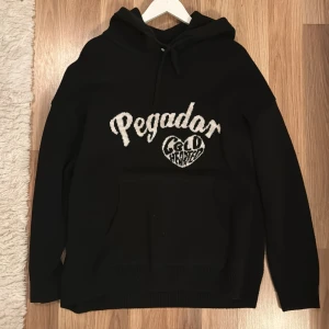 Hoodie/Huvtröja - Hoodie från Pegador. Broderat tryck. Storlek L men stor i storlek och oversize passform så passar även XL. Inga skador eller fläckar!