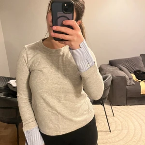 Tröja med fin detalj - Grå tröja med ”skjortärmar”. Fin och knappast använd. Härlig till höst/våren 🍂 ☀️ 