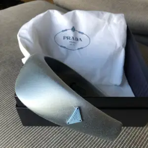 Nytt Daidem från Prada i vacker ljus gråblå färg. Aldrig använt. Dustbag, box och kvitto medföljer.
