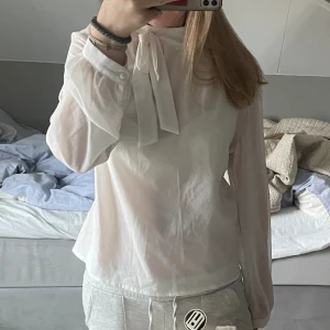Vit blus - Säljer min fina, lite lyxiga blus med knytning i halsen. Den är knappt använd och har inga defekter. Den är en aning genomskinlig men funkar bra med linne under🥰