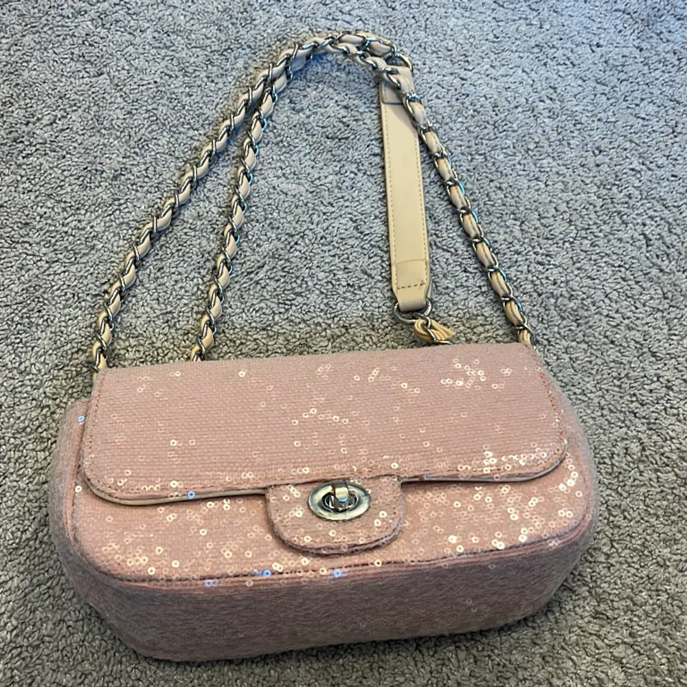 Fin väska från Gina Tricot som har glitter paljetter och den e rosa med silver kedja runt om de beiga banden!💕❤️. Väskor.