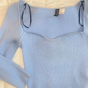 Magtröja med fin design - Ljusblå tröja, den är finare än vad den ser ut på bild eftersom den töjs ut vid magen beroende på ens kroppstyp, den är ganska stretchiga o är använd fåtal gånger då den är lite nopprig annars är den i bra skick! 