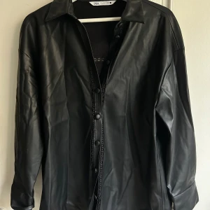 Skjorta i skinnimitation med detaljer  - Superfin Skjorta i skinnimitation med detaljer, aldrig använd. 