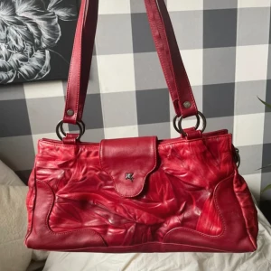 Röd vintage handväska - Säljer en supersnygg röd väska i mycket bra skick (något slitet runt hörnen) Längd 40 cm Höjd 19 cm  