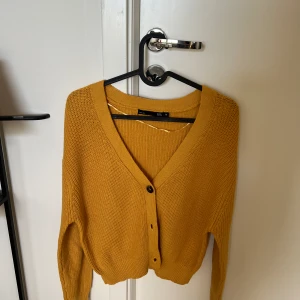 Kofta  - Gul kofta med brunsvarta knappar. 