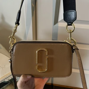Marc Jacobs The Snapshot väska -guld  - 🤎Säljer min otroliga Marc Jacobs väska.🤎Väskan är som i ett nytt skick, och kvitto finns! Ursprungspris 4000, säljer för ca 1500, pris kan diskuteras! 
