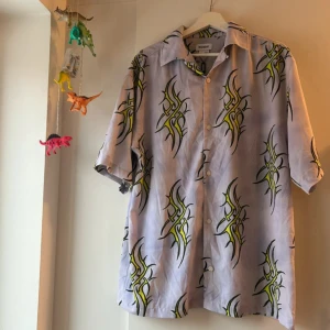 Kortärmad skjorta Weekday tribal neon y2k  - Kortärmad skjorta med neon-tribaler. Knappar framtill. Storlek S. Den kommer från Weekday. 