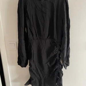 Svart kort klänning  - Svart kort klänning med snörning vid ena sidan