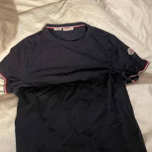 Moncler t-shirt - Säljer nu min äkta moncler t-shirt som går även att scanna. För fler bilder eller frågor så är det bara att skriva! Inga defekter eller fläckar. Är väldigt mörkblå i färgen, köparen står alltid för frakten!🩷