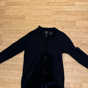 Svart jacka - En blå tröja i merinoull med knappar framtill. tröjan är helt i nyskick. storlek M men passar även S