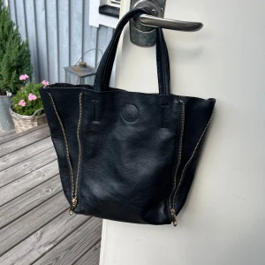 Svart väska - Svart väska med gulddetaljer som rymmer mycket. Kort och långt band. 