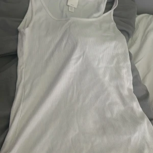 Vit ribbad linnetopp från H&M - En vit ribbad linnetopp från H&M Basics. Toppen är ärmlös och har en rund halsringning.