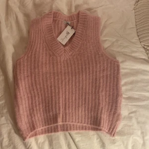 V ringad stickad väst  - Ljusrosa stickat väst från märket design by si i storlek xs/s. Den är i väldigt bra skick då den endast har används när jag har provat den på. Lappen är även kvar och den är som sagt V ringad! 