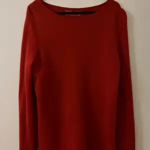 Röd ulltröja från Gerry Weber med dekorativa knappar längs ryggen i storlek 38. 100% ull. Tröjan är i nyskick då använd 1-2 ggr. Tröjan är tvättad.   Mått:  Längd ca 65 cm  Byst ca 48 cm Ärmar ca 65 cm
