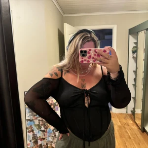 Svart topp från Shein - En svart topp från Shein med långa ärmar i genomskinligt material och en knytning framtill. Toppen har en åtsittande passform och är tillverkad i ett glansigt tyg. Använd en gång. Storlek 2XL 