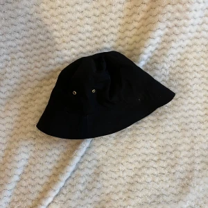 Svart buckethat - Svart buckethat med guld-detaljer från H&M. Najs passform. Knappt använd!