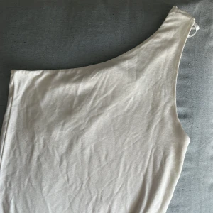 En axlad Topp  - En axland topp från Gina tricot med prislappen kvar och aldrig använd. Super söt men säljer för att den aldrig används💕