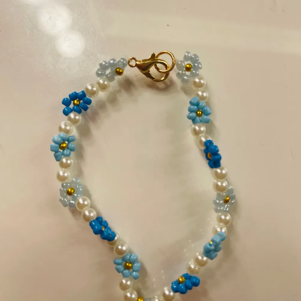 ett fint och somrigt armband med blommor av olika nyanser av blå!. Asusteet.