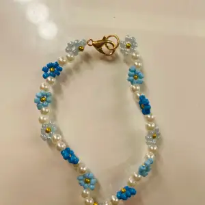 ett fint och somrigt armband med blommor av olika nyanser av blå!