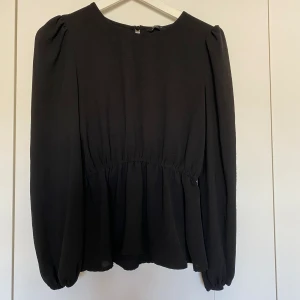 Svart blus  - Svart blus med volang/resår nedtill. Storlek XS från Only