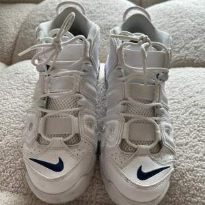 Nike skor i bra skick. Nypris 2199 kr, använd fåtal gånger.   The Nike Air More Uptempo '96 hämtar tillbaka en klassisk basketstil till gatan. Den mellanhöga retrosneakern har en helvit färgsättning, synlig Air-stötdämpning i fullängd och elastiska r