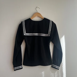 Sailortopp/sjömanstopp i svart, XS - Supersöt sailortröja/sjömanströja i svart med fin krage. Storlek XS!  Sparsamt använd och i fint skick! Har passande kjolar till denna bland övriga aktioner!