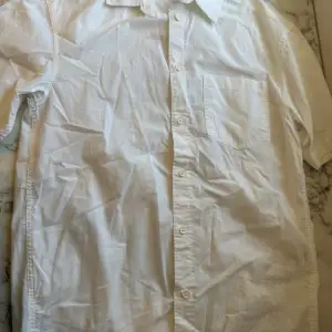 Vit kortärmad skjorta från HM i storlek S. Passformen är relaxed fit vilket med dess vita färg är en perfekt kombination för sommaren. Använts endast 1-2 gånger så är mer eller mindre ny. Sitter bra på kroppen och funkar bäst med ett par svarta jeans