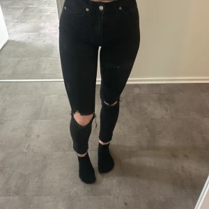 Svarta jeans  - Svarta högmidjade jeans med hål i knäna  från nakd. Sparsamt använda! 