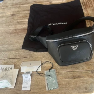Äkta Armani midjeväska märkeskläder  - Köpte en Armani väska nere i Milanos flygplats. Köpt i deras egna butik med kvitto samt alla tags osv kan styrka att den är 1000% äkta. Använd en handfull gånger då jag är mer bekväm med dom gamla. Köpt för 240 euro i februari detta år vilket är 2784