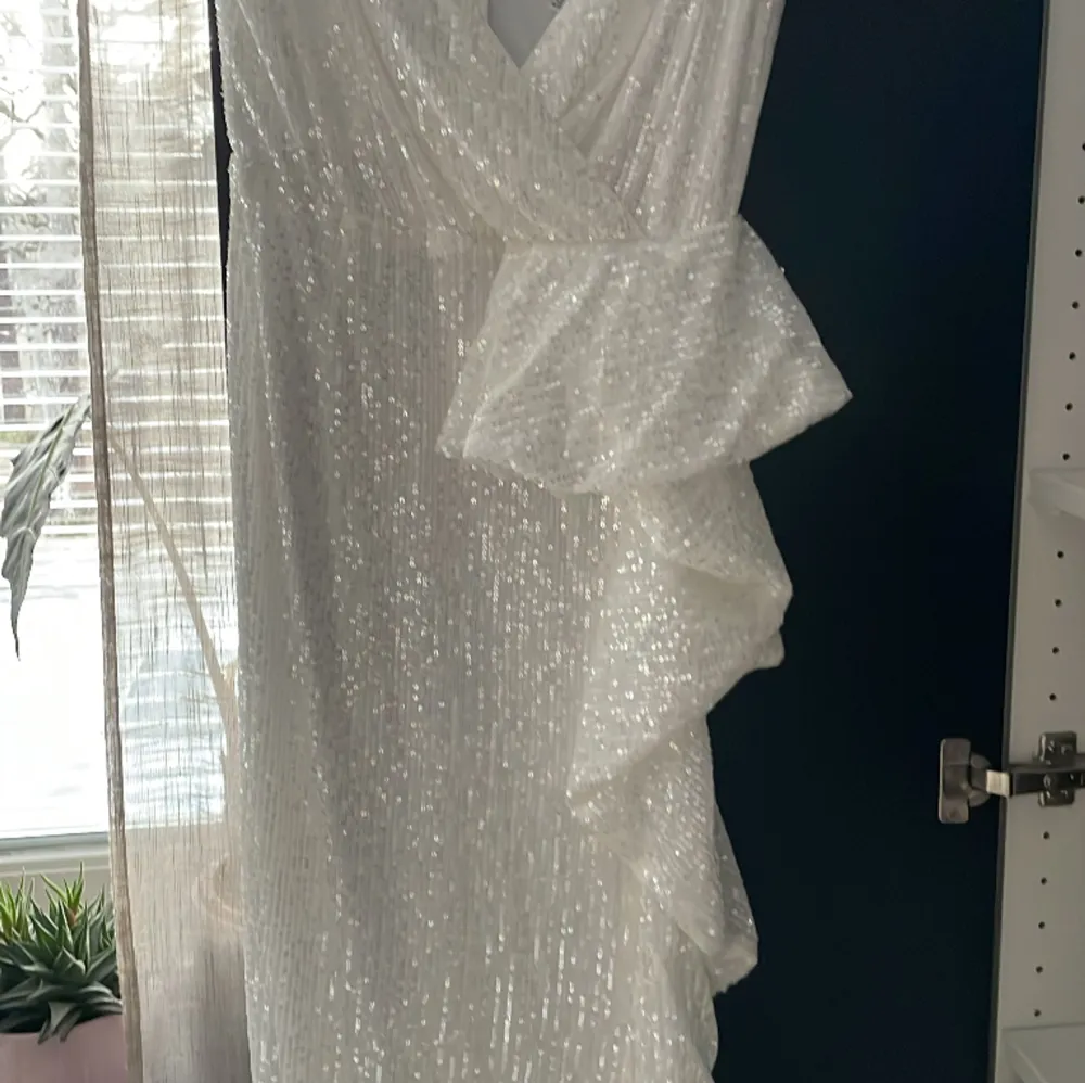 En vitt glittrig klänning i storlek M, lång, fin öppning vid brösten     (oanvänd) öppet på högra sidan av benet . Klänningar.
