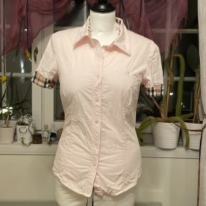 Rosa burberry skjorta  - En jättegullig ljusrosa kortärmad burberry skjorta i bra skick! Det står att den är i storlek L, men den passar XS-S 