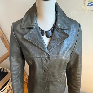 Skinnjacka - (Mörk) grön vintagejacka med figur. Väldigt gott skick, grön invändigt. Passar både Storlek S & M . 