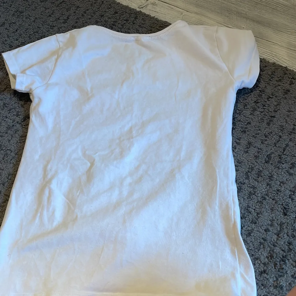 En vit t-shirt med en ängel på. Köpt utomlands i st M men passar även S. Har ett hål som vi ha lagat men märks knappast. T-shirts.