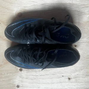 Nike Air Zoom Mercurial Vapor 15 Pro FG Shadow - Svart/Krom/Blå - Storlek 39 Känns tight på foten Har använt ett par gånger men ändå i bra skick. Anledningen jag säljer är för små 