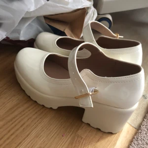 Vita Mary Janes - Dem är i storlek 36 och har blivit använda ett par gånger men är fortfarande i bra skick. Bilden är från när dem var nya och dem har lite smuts på sig nu men ingenting alldeles för synligt. Dem har en rätt så hög klack så bra om man vill ha mer längd