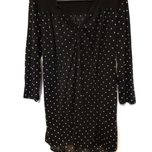 Prickig gravidtröja strl. M - Svart gravidtröja/tunika med vita prickar i storlek M från Hm. Är tillverkad av ett lite tunnare material och har knyt i ryggen. I fint begagnat skick, inga hål eller fläckar.  Tvättad i parfymfritt tvättmedel och utan sköljmedel.