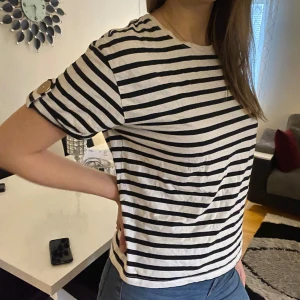 Randig t-shirt från Zara - En randning t-shirt från Zara med guldiga knappar på armarna. 