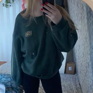 Grön sweatshirt med tryck på ryggen