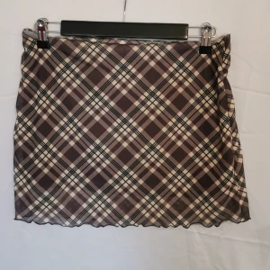 Rutig kjol - Säljer denna rutiga kjol då den är för liten för mig. Den är ganska kort mem stretchig, funkar som low waist. Den ser brun ut på bilden men den är mer grå i verkligheten. 
