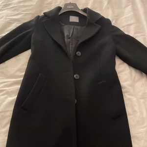 Kappa - Svart medellång kappa med knappar i mycket bra skick